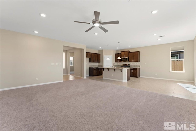 unfurnished living room featuring sink, light carpet, and ceiling fan