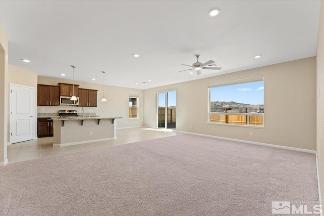 unfurnished living room featuring light carpet, sink, and ceiling fan