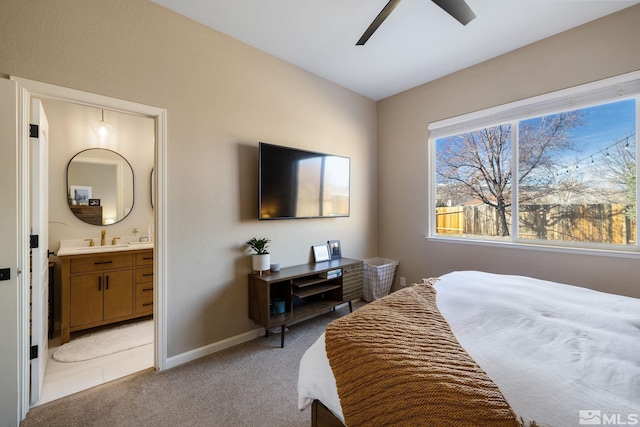 bedroom with connected bathroom, sink, light carpet, and ceiling fan