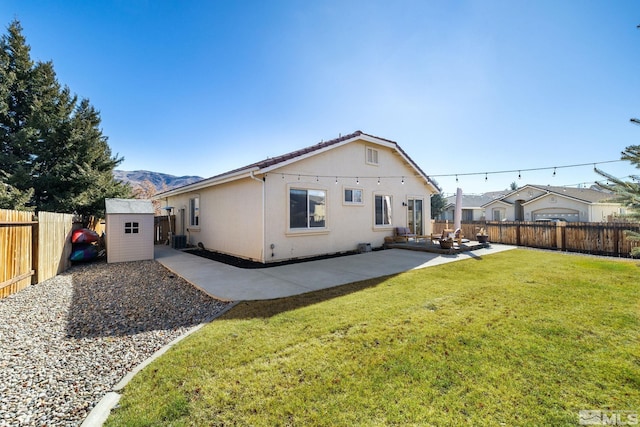 rear view of house with a lawn, a patio, and a storage unit