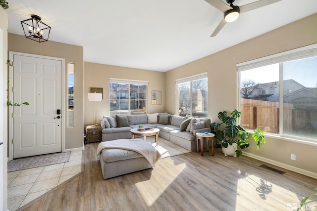 living room with ceiling fan with notable chandelier and light hardwood / wood-style flooring