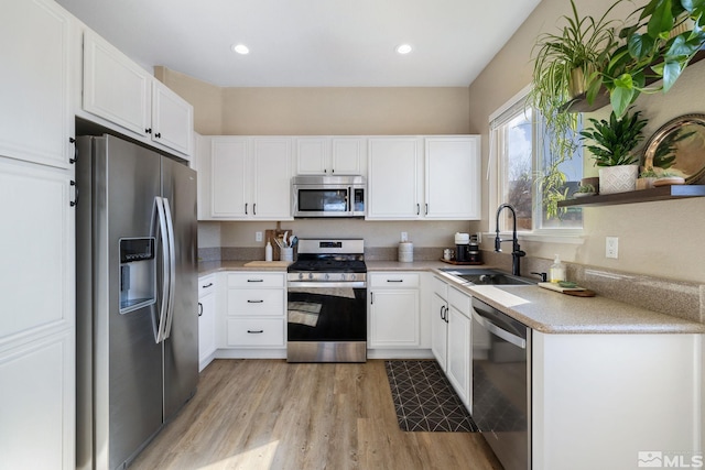 kitchen featuring sink, light hardwood / wood-style flooring, stainless steel appliances, and white cabinets