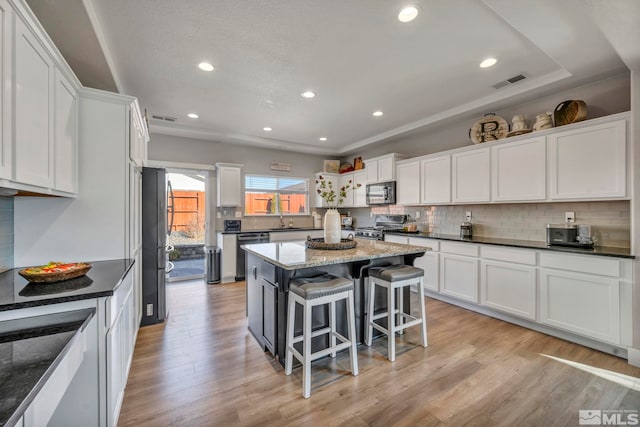 kitchen with appliances with stainless steel finishes, a kitchen breakfast bar, a center island, and white cabinets