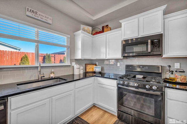 kitchen featuring white cabinets, sink, dark stone countertops, and range with gas stovetop