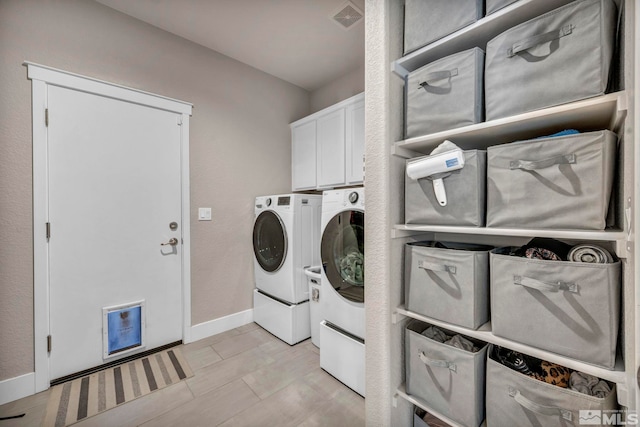 washroom featuring cabinets and washing machine and dryer