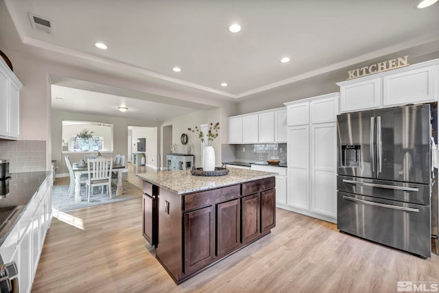 kitchen featuring dark brown cabinetry, a tray ceiling, stainless steel fridge, and white cabinets