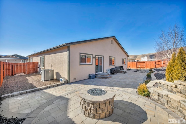 rear view of property featuring a patio, central AC unit, and an outdoor fire pit