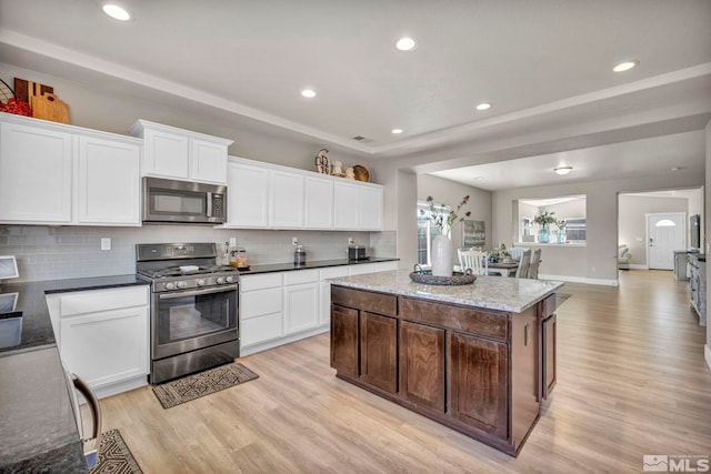 kitchen with white cabinetry, stainless steel appliances, a center island, and light hardwood / wood-style flooring