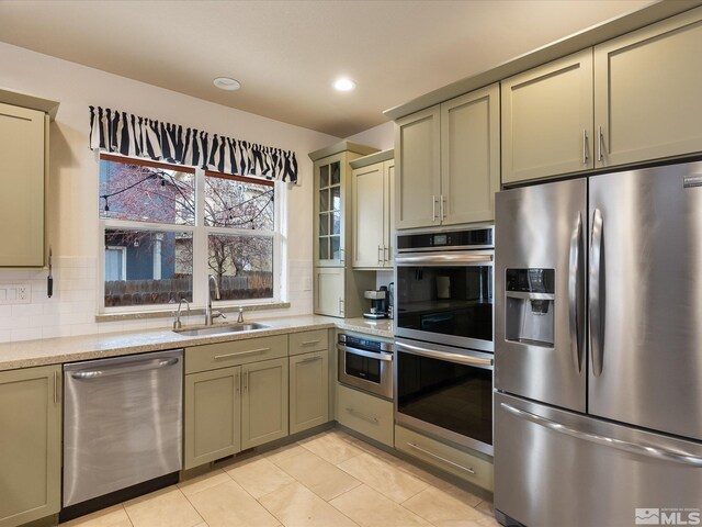 kitchen featuring sink, decorative backsplash, stainless steel appliances, and light tile patterned floors