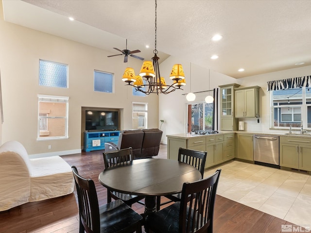 dining space with an inviting chandelier, sink, a high ceiling, a textured ceiling, and light hardwood / wood-style flooring