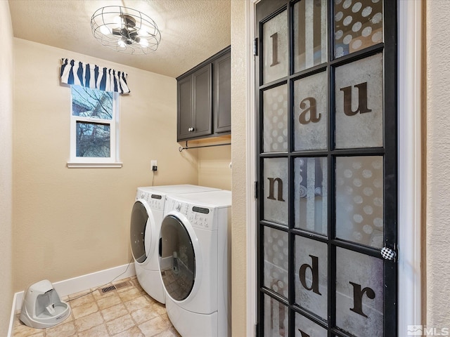 washroom featuring washing machine and dryer, cabinets, and a textured ceiling