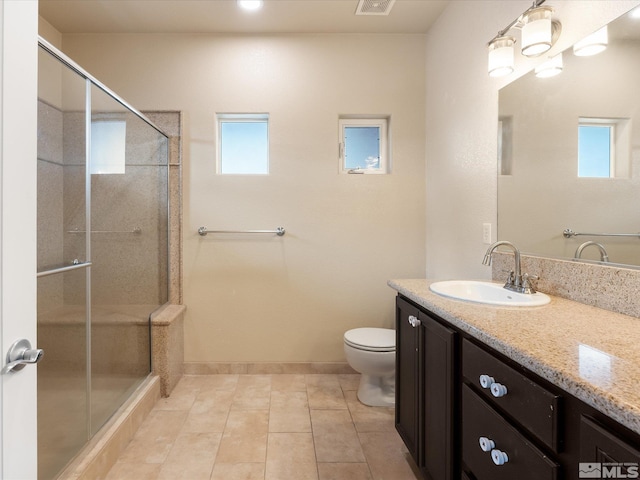 bathroom featuring toilet, vanity, tile patterned floors, and a shower with shower door