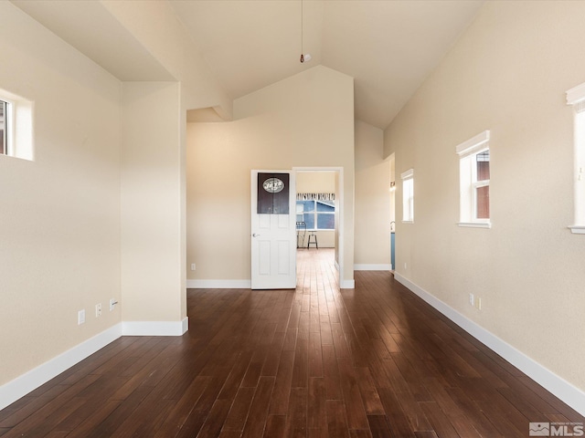 empty room featuring dark wood-type flooring and high vaulted ceiling