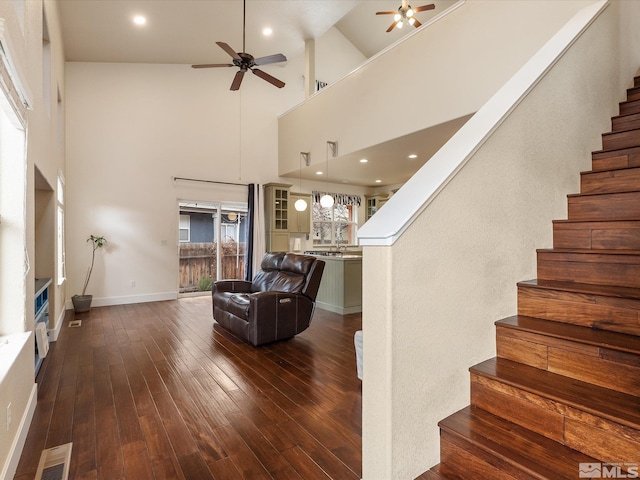 living room featuring ceiling fan, dark hardwood / wood-style flooring, and a towering ceiling