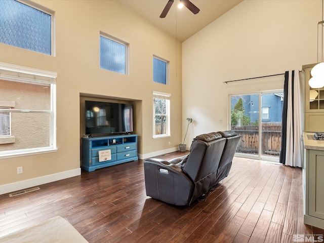 living room featuring dark wood-type flooring, a healthy amount of sunlight, and high vaulted ceiling