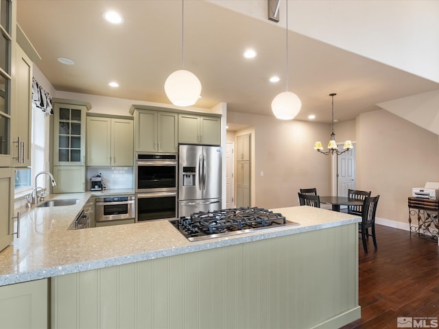 kitchen featuring sink, hanging light fixtures, light stone counters, stainless steel appliances, and dark wood-type flooring