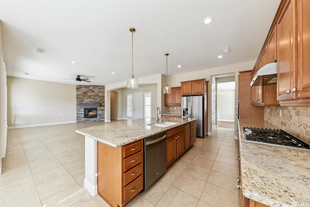 kitchen featuring light stone counters, tasteful backsplash, decorative light fixtures, stainless steel appliances, and a large island