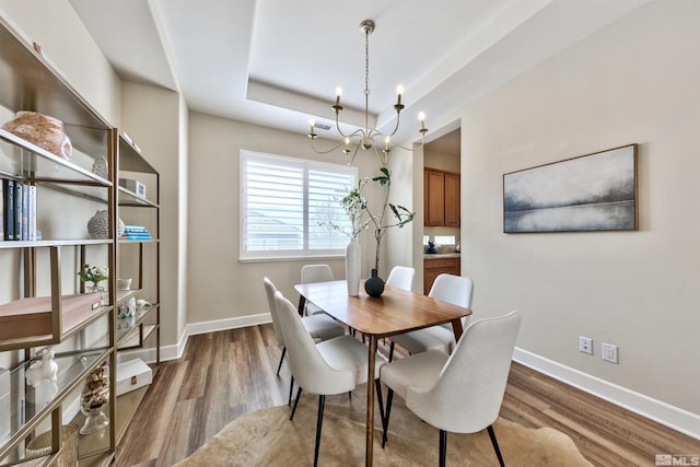 dining space with hardwood / wood-style floors and a raised ceiling