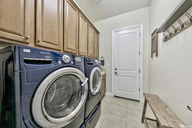 clothes washing area with cabinets, separate washer and dryer, and light tile patterned floors