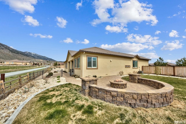 rear view of house with a patio, a yard, an outdoor fire pit, a mountain view, and central AC