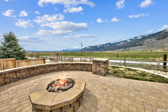 view of patio featuring a mountain view, a rural view, and a fire pit