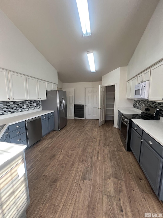 kitchen with tasteful backsplash, white cabinetry, blue cabinets, dark hardwood / wood-style flooring, and stainless steel appliances