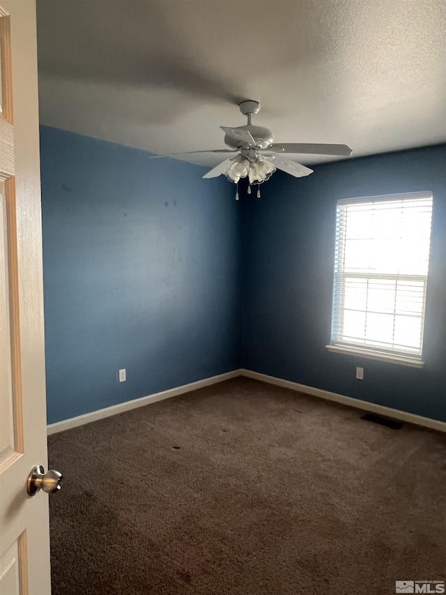 carpeted empty room featuring ceiling fan and a textured ceiling