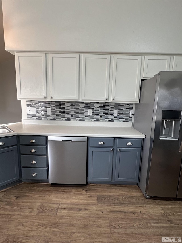 kitchen featuring tasteful backsplash, dark wood-type flooring, white cabinets, and appliances with stainless steel finishes