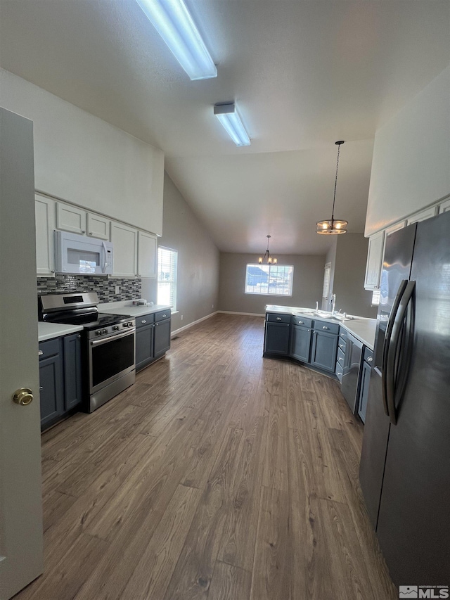 kitchen with hardwood / wood-style flooring, stainless steel appliances, decorative light fixtures, and gray cabinetry