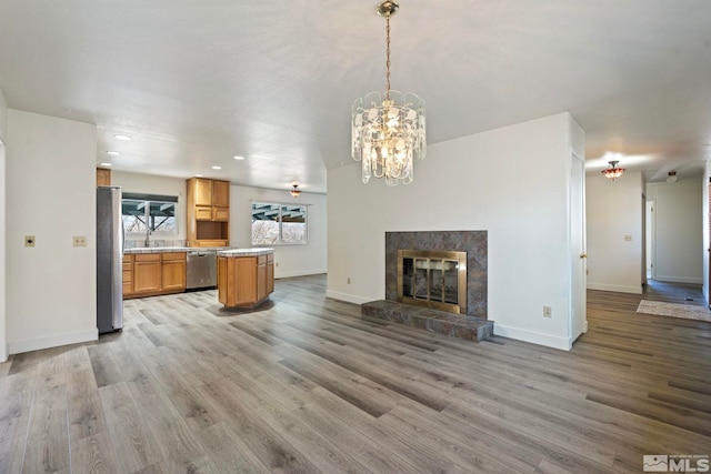 kitchen featuring hanging light fixtures, stainless steel appliances, a tile fireplace, and light wood-type flooring