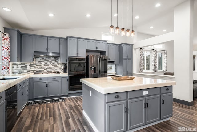 kitchen with lofted ceiling, pendant lighting, appliances with stainless steel finishes, gray cabinetry, and a center island