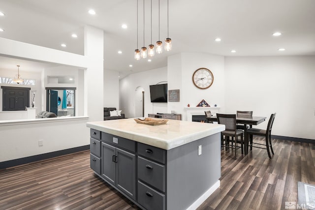 kitchen featuring lofted ceiling, dark wood-type flooring, gray cabinetry, hanging light fixtures, and a kitchen island