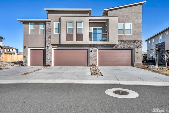 view of front facade featuring a garage, stone siding, concrete driveway, and stucco siding