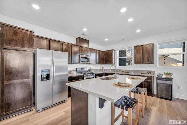 kitchen with wine cooler, stainless steel appliances, a sink, visible vents, and dark brown cabinets