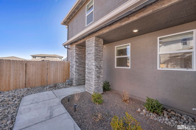 entrance to property with fence and stucco siding