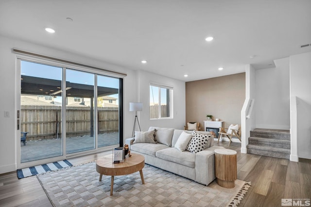 living area featuring baseboards, stairway, wood finished floors, and recessed lighting