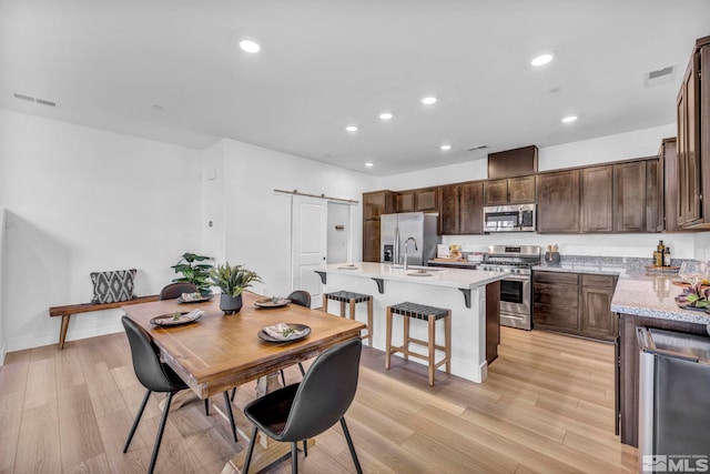 dining room with a barn door, visible vents, light wood-style flooring, and recessed lighting