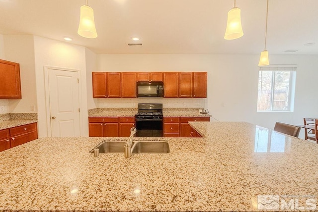 kitchen featuring light stone counters, sink, black appliances, and hanging light fixtures