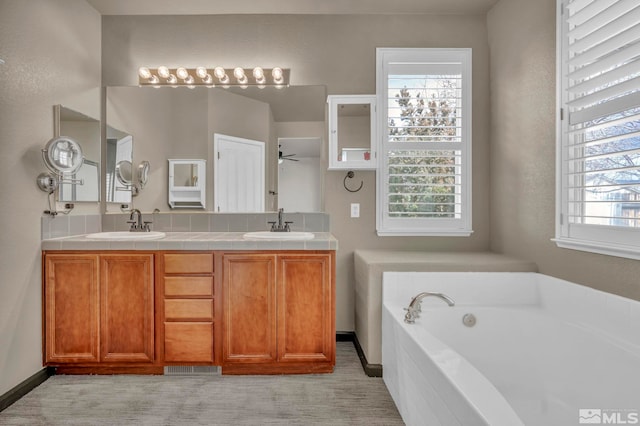 bathroom with ceiling fan, vanity, and a bathing tub