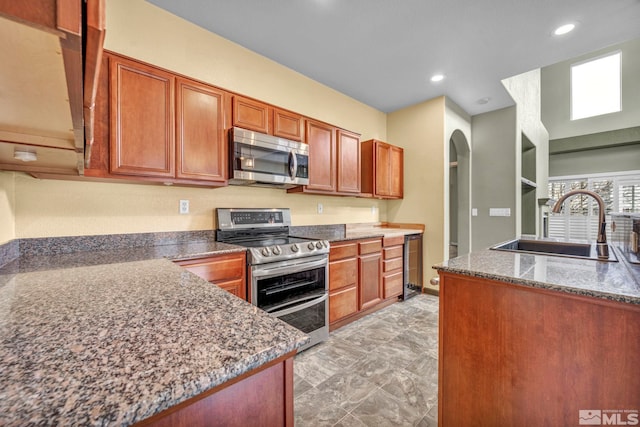 kitchen with stainless steel appliances, sink, and dark stone counters