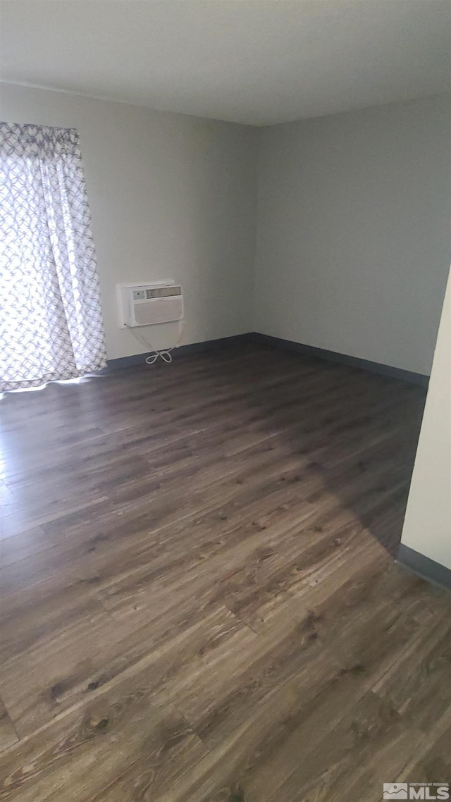 spare room featuring dark wood-type flooring and a wall unit AC