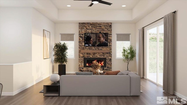 living room with hardwood / wood-style flooring, ceiling fan, and a stone fireplace