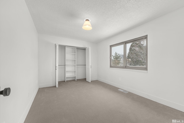 unfurnished bedroom featuring carpet flooring, a textured ceiling, and a closet