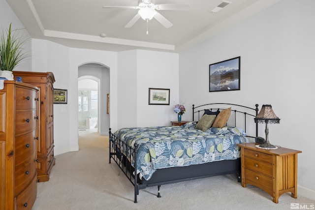 carpeted bedroom with ceiling fan and a tray ceiling