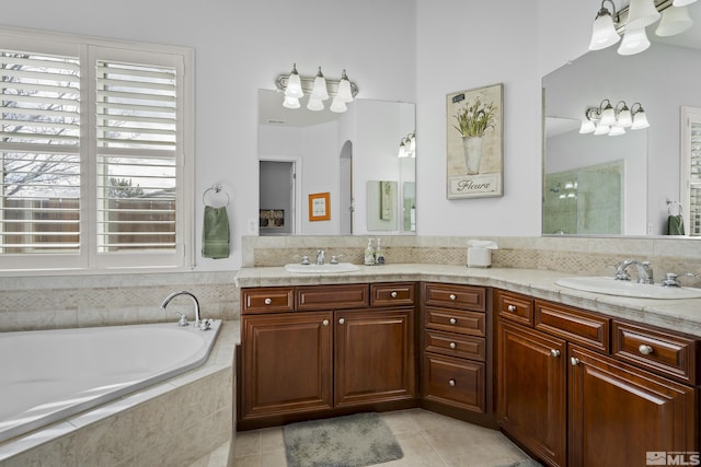 bathroom featuring tile patterned floors, vanity, and tiled bath