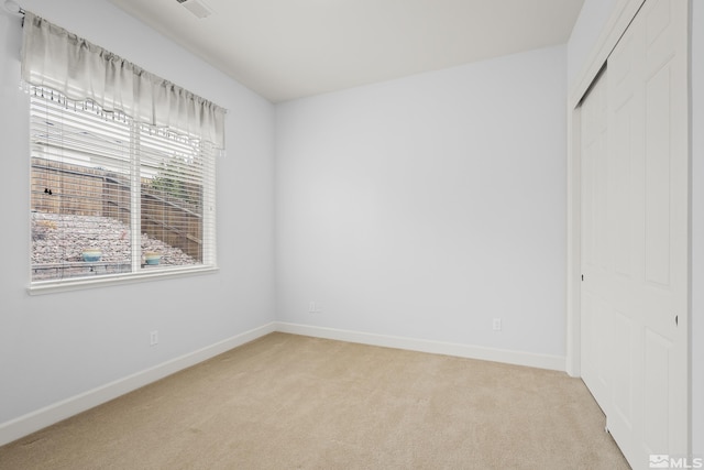 unfurnished bedroom with light carpet and a closet