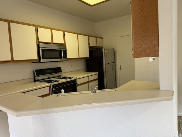 kitchen with cream cabinets, sink, stainless steel appliances, and kitchen peninsula