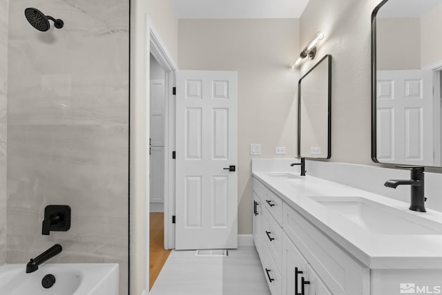 bathroom with hardwood / wood-style flooring, vanity, and tiled shower / bath