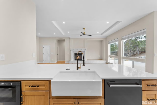 kitchen featuring sink, a tray ceiling, kitchen peninsula, and light brown cabinets