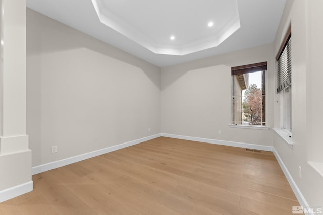 unfurnished room with light hardwood / wood-style flooring, ornamental molding, and a raised ceiling